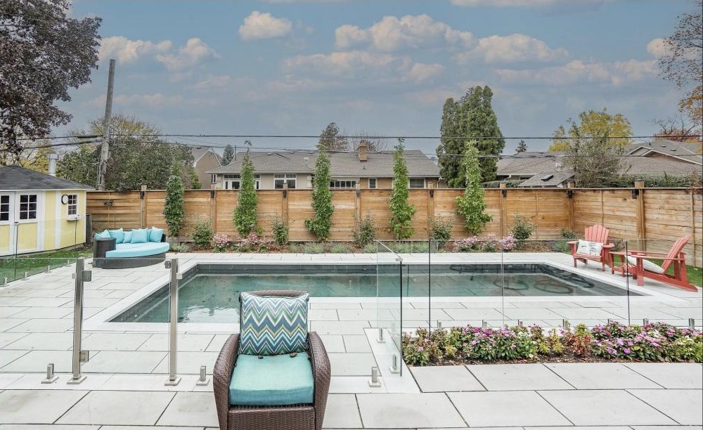 Glass-fenced pool terrace with lounging and dining areas