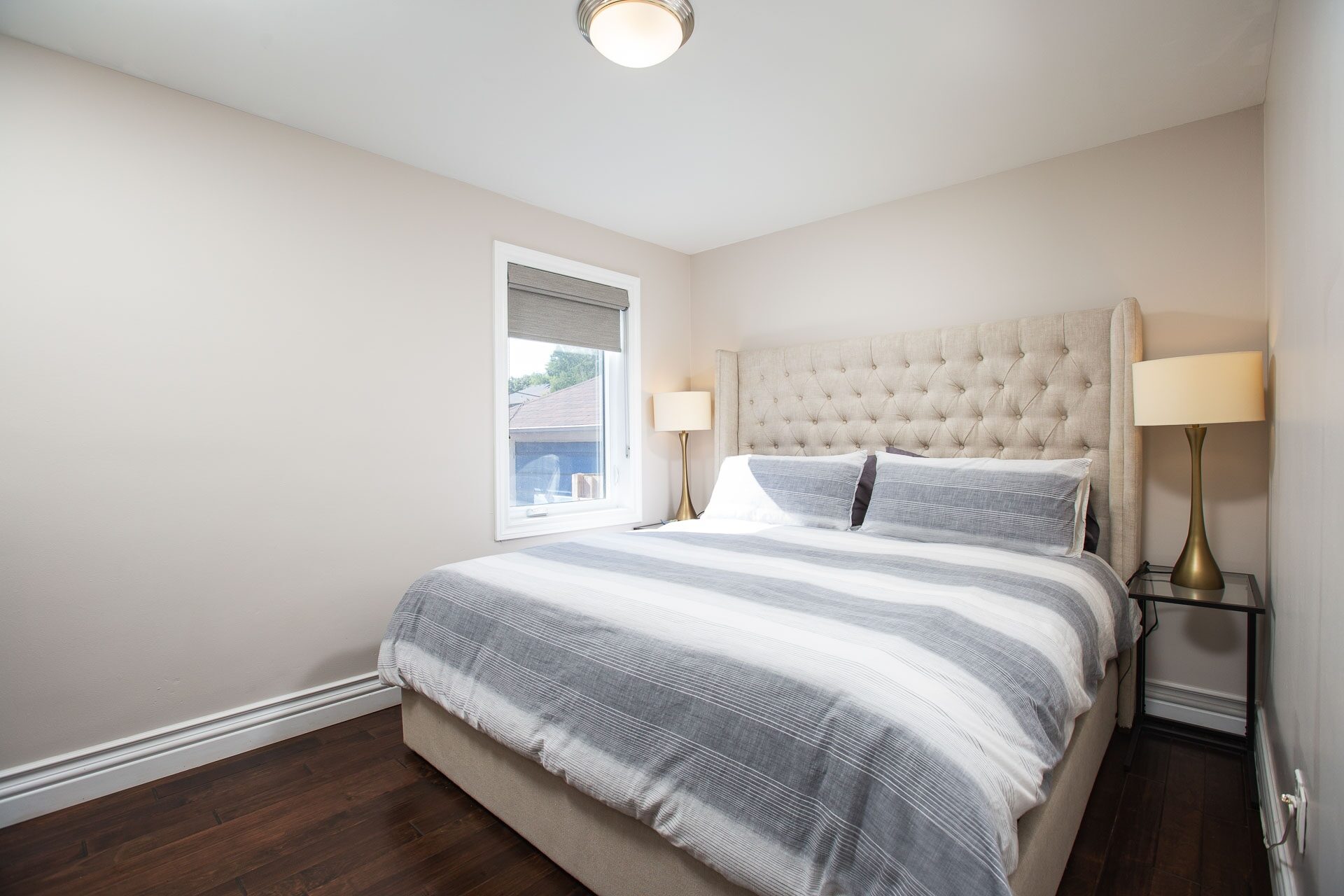 Primary bedroom with upholstered bed and natural light
