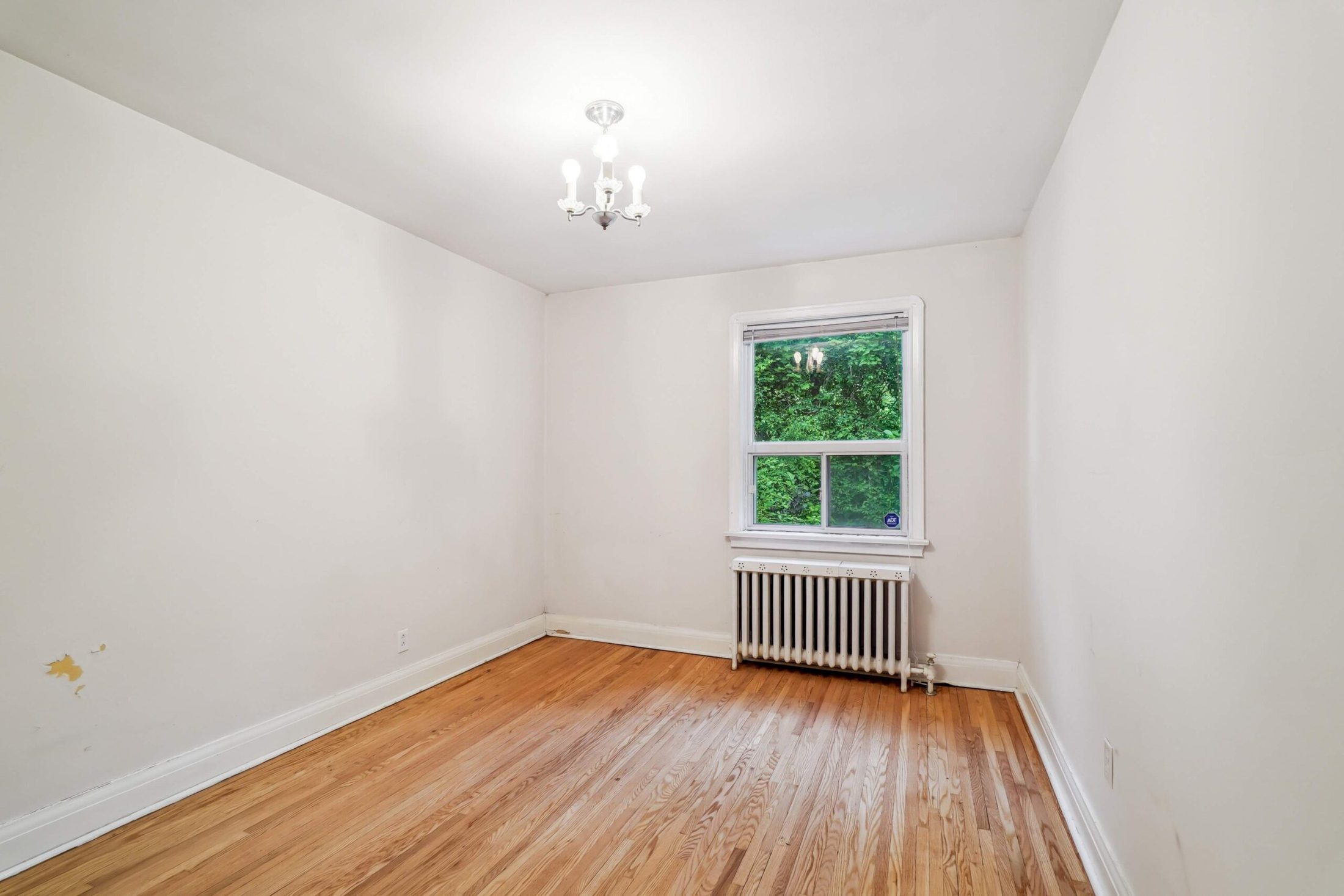 Principal bedroom with hardwood floors and garden-view window