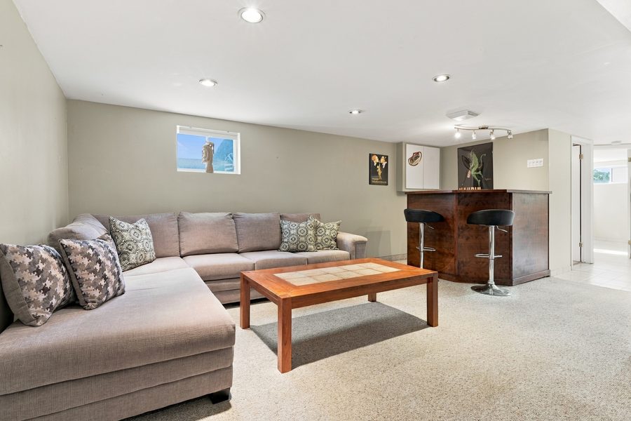 Finished lower level recreation room with sectional seating and a bar