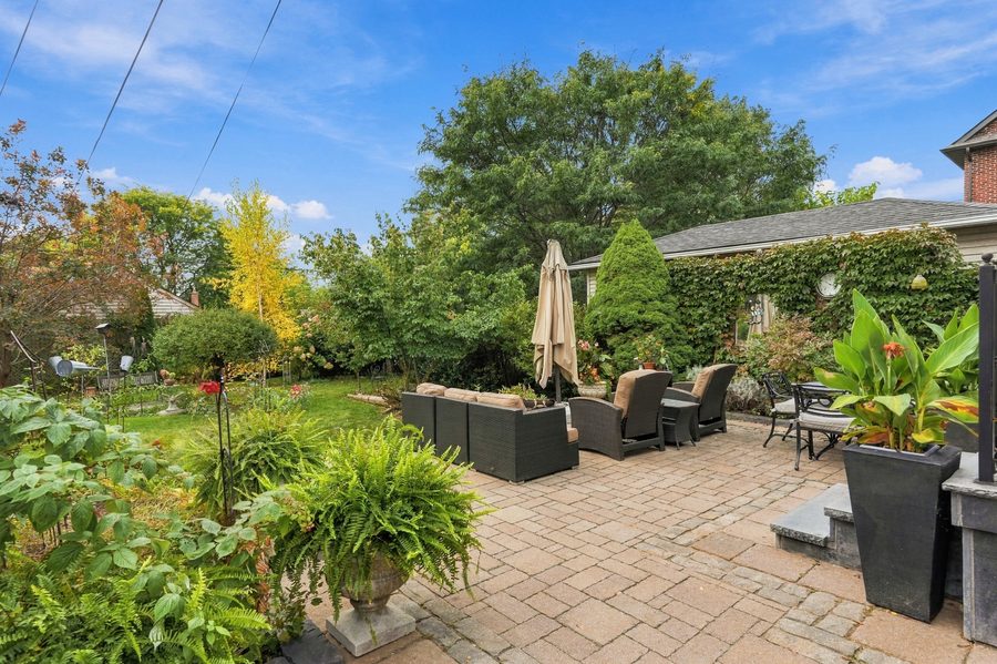 Rear stone patio with outdoor seating and lush planting